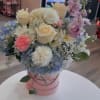 Soft pastels and garden-fresh texture make this hat-box bouquet a gentle celebration