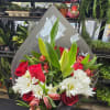 Handheld bouquet of red roses, white daisies, lilies, and alstroemeria in gray paper wrap