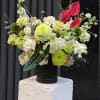 Mixed floral arrangement with white, green, and red blooms in a black vase