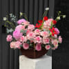A lush cluster of deep red roses arranged in a rectangular woven