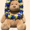 Teddy bear wearing a blue, purple, and yellow flower lei