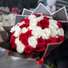 Bouquet of red and white roses wrapped in dark paper
