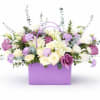 Soft lavender and white blooms spill from a lavender gift bag to