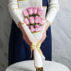 A compact cluster of soft pink roses makes this wrapped bouquet an