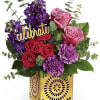 Bright arrangement of pink and red roses with purple flowers in a gold cube vase with a celebrate sign.