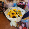 Bouquet of yellow sunflowers with white filler flowers in cream wrapping