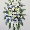 A tall, dignified standing spray in cool white, blue, and green tones