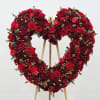 A dense heart of red and burgundy roses, accented with bright red