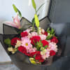 A compact cluster of deep red roses and pale pink chrysanthemums makes