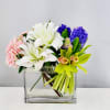 Compact clear rectangular vase of white lilies, pink roses, purple hyacinth and