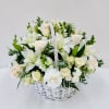 White wicker basket overflowing with white lilies, roses, carnations and snapdragons with