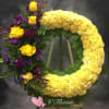 Circular floral wreath with yellow flowers and purple roses on an easel