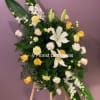 Standing floral spray with white lilies, yellow roses, and white orchids