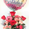 Birthday balloon above a rose bouquet in a glass vase