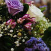 Bouquet of purple and white roses with small filler flowers