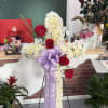 Cross-shaped floral tribute with red and white roses and a lavender ribbon