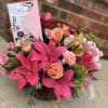 Pink flower basket with lilies, roses, and a Mother's Day card