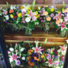 Assorted colorful flower bouquets arranged on wooden shelves in glass jars