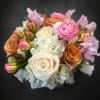 Soft white and blush roses crown this compact arrangement, a rounded bouquet