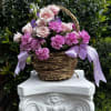 Pink roses and carnations in a wicker basket with lavender ribbons