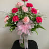 Pink and light pink carnations in a glass vase with a pink ribbon bow