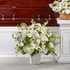 White funeral arrangement in a vase beside a casket