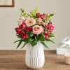 Pink and red mixed flower arrangement in a white vase