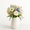Soft white roses mingle with pale alstroemeria and cool blue delphinium to