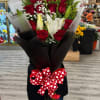 Tall wrapped bouquet of red roses and white lilies with a red heart-print bow