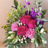 A lush cascade of vivid pink roses and ruffled pink carnations greets