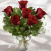 This arrangement has six roses, greens and a clear glass vase. If