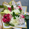 Bouquet of pink roses, white chrysanthemums, and lilies wrapped in pastel paper
