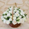 A round cluster of white roses gathered in a hand-carried wicker basket
