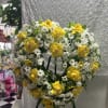 Heart-shaped floral wreath with yellow roses and white daisies on an easel