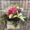 A beautiful purse-inspired floral arrangement featuring vibrant pink roses, creamy white lilies