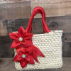 A handcrafted woven straw handbag trimmed with satin ribbon flowers and sparkling