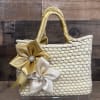 A handcrafted woven straw handbag trimmed with satin ribbon flowers and sparkling