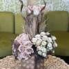 Pink and white rose arrangement in a textured vase with dried grasses