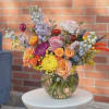 Mixed bouquet of roses, chrysanthemums, and delphinium in a glass vase