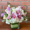 Pink and white bouquet with orchids and roses in a square glass vase