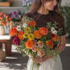 A lively mix of orange and pink roses gives this hand-tied flower