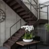 White orchid arrangement in a shallow white bowl on a wooden table