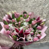 Pink tulip bouquet with white daisies and a dark lily in pink wrap
