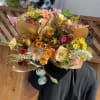 Person holding several colorful mixed flower bouquets wrapped in paper