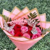 A tightly clustered hand-tied bouquet Ramo of pink and red roses that