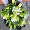 Bouquet of white lilies with green buds and leaves, wrapped in plastic