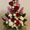 Deep, velvety red roses rise through clusters of soft white carnations and