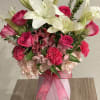 Bright white lilies rise above vivid hot-pink roses and carnations in this