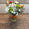 A cheerful cluster of orange tulips and crisp white daisies topped with