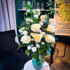 White roses and carnations in a teal glass vase